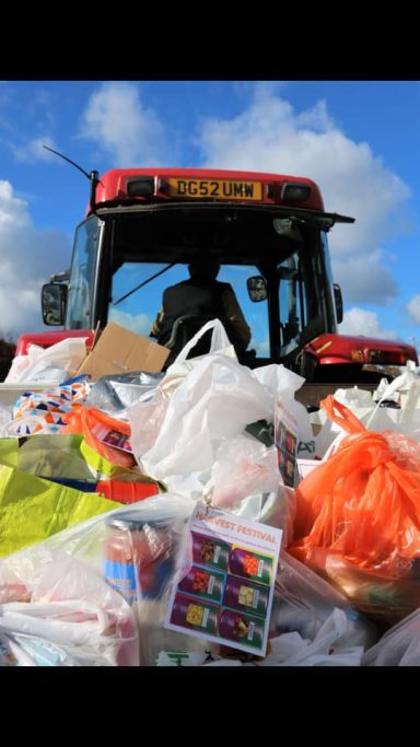 A red lorry surrounded by a large pile of assorted waste materials.